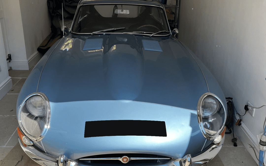 Front view of a light blue classic sports car inside workshop in Swindon